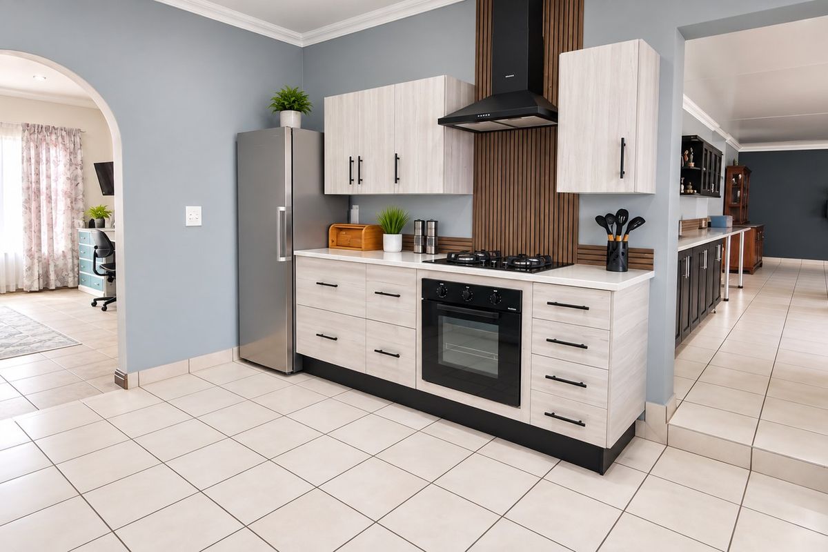 Modern kitchen featuring light wood cabinetry, a gas hob with extractor fan, built-in oven, and tiled flooring, seamlessly integrated into the open-plan living space.