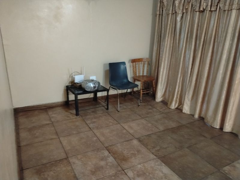 A sparsely furnished living area featuring neutral wall finishes and large format floor tiles, offering a blank canvas for interior design updates.