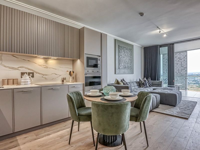 Modern open-plan apartment featuring a sleek kitchen with integrated appliances, marble-look splashback, and seamless flow to the living area and balcony.