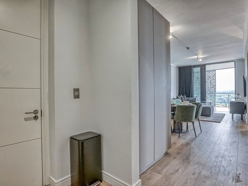An open-plan living area featuring modern laminate flooring, built-in cabinetry, and a seamless transition to a balcony with expansive views.