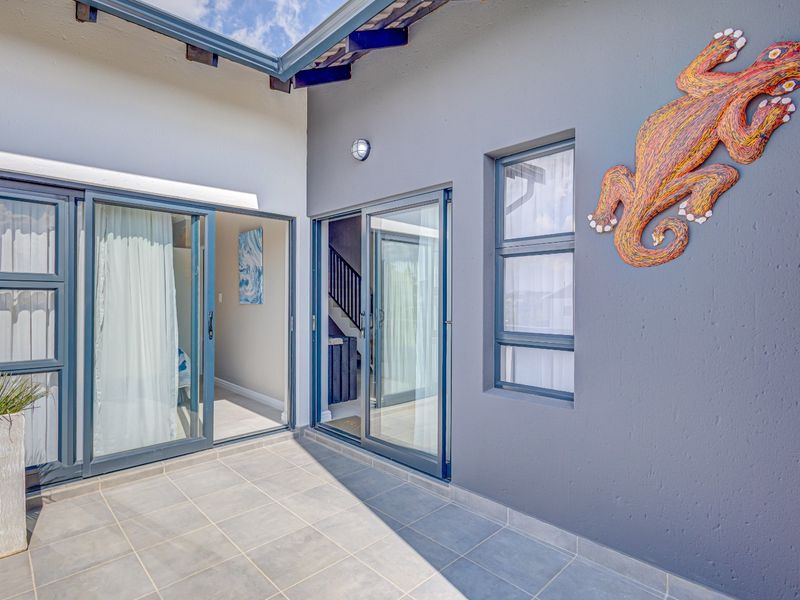 A well-maintained covered patio area featuring tiled flooring, exposed rafters, and sliding glass doors providing access to the interior living spaces.