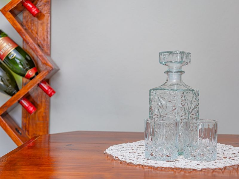 A close-up shot of a glass decanter and glasses on a wooden surface with a wine rack visible in the background.