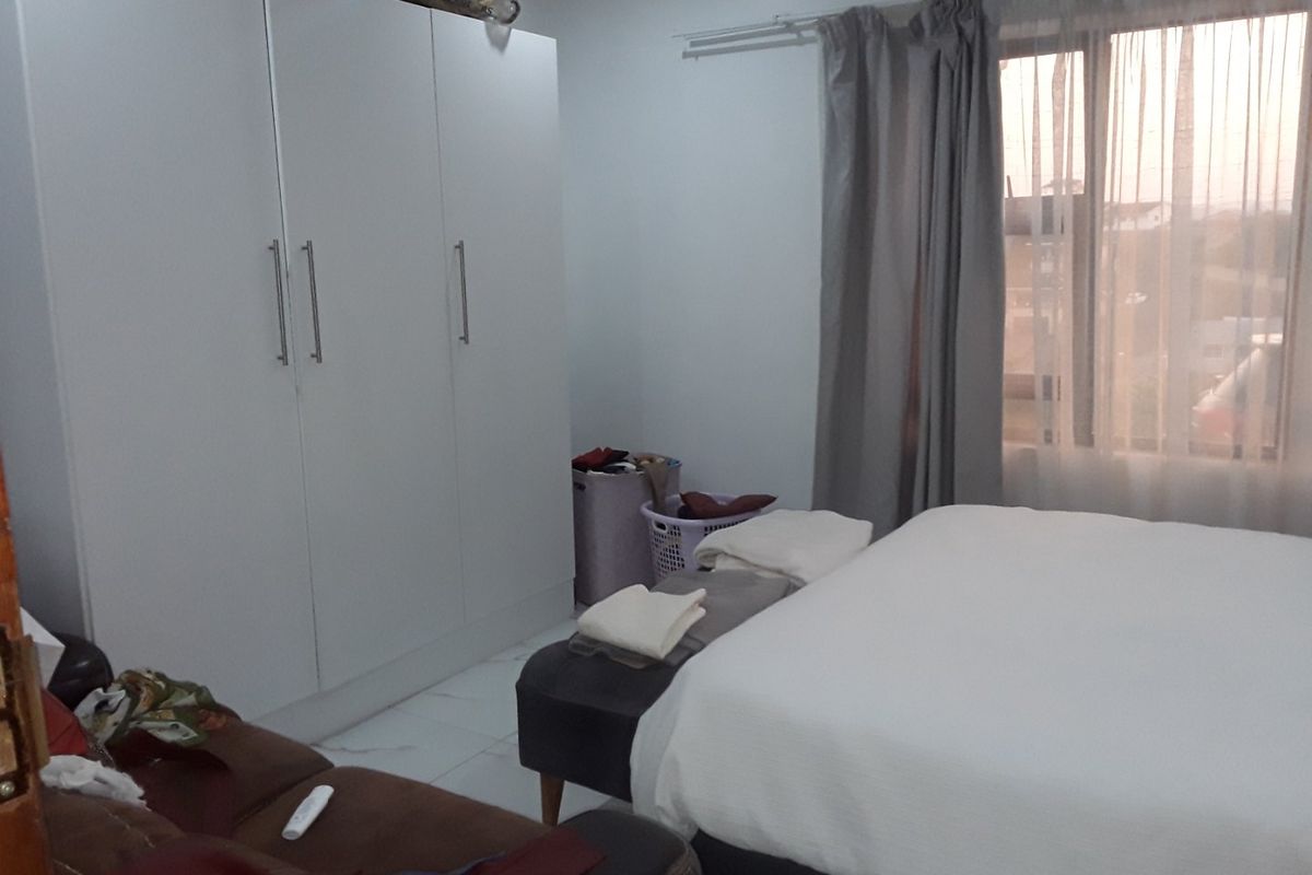 A bedroom featuring tiled flooring and a large built-in wardrobe with white cabinetry.