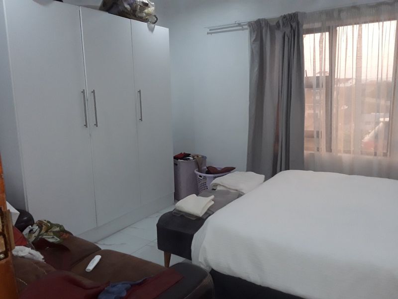 A bedroom featuring tiled flooring and a large built-in wardrobe with white cabinetry.