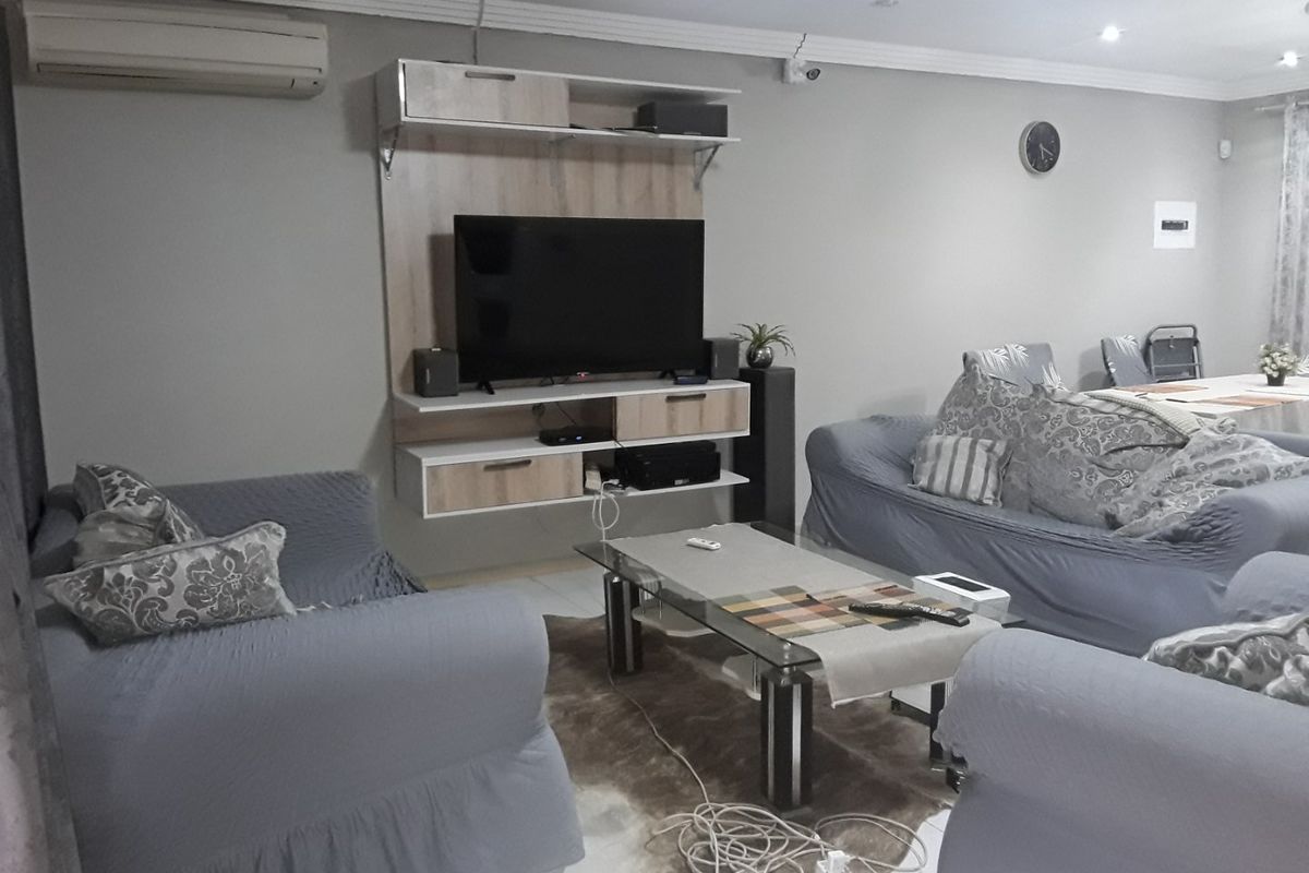 A living room featuring a wall-mounted air conditioning unit, built-in media cabinetry, and decorative cove cornicing with recessed lighting.