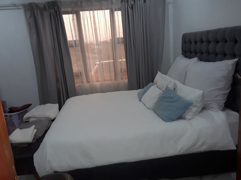A bedroom featuring a large window with installed curtain rails, providing natural light and a view of the exterior.