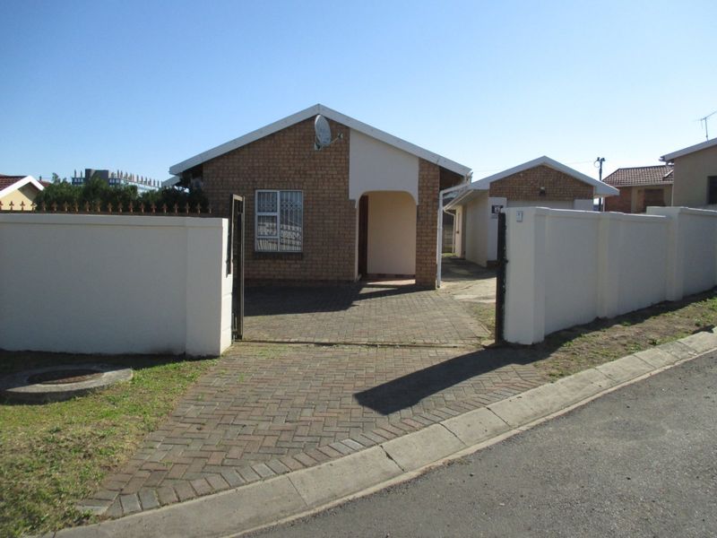 Front view of a face brick house featuring a paved driveway, secure perimeter wall, and gated entrance.