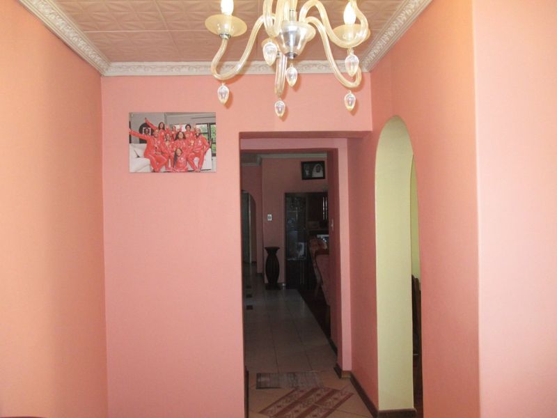 A hallway featuring decorative ceiling tiles, crown molding, and an arched entryway leading to adjacent living spaces.