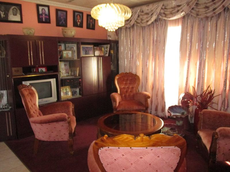 A traditional living room featuring built-in cabinetry and a decorative central light fixture, with carpeted flooring and heavy window drapery.