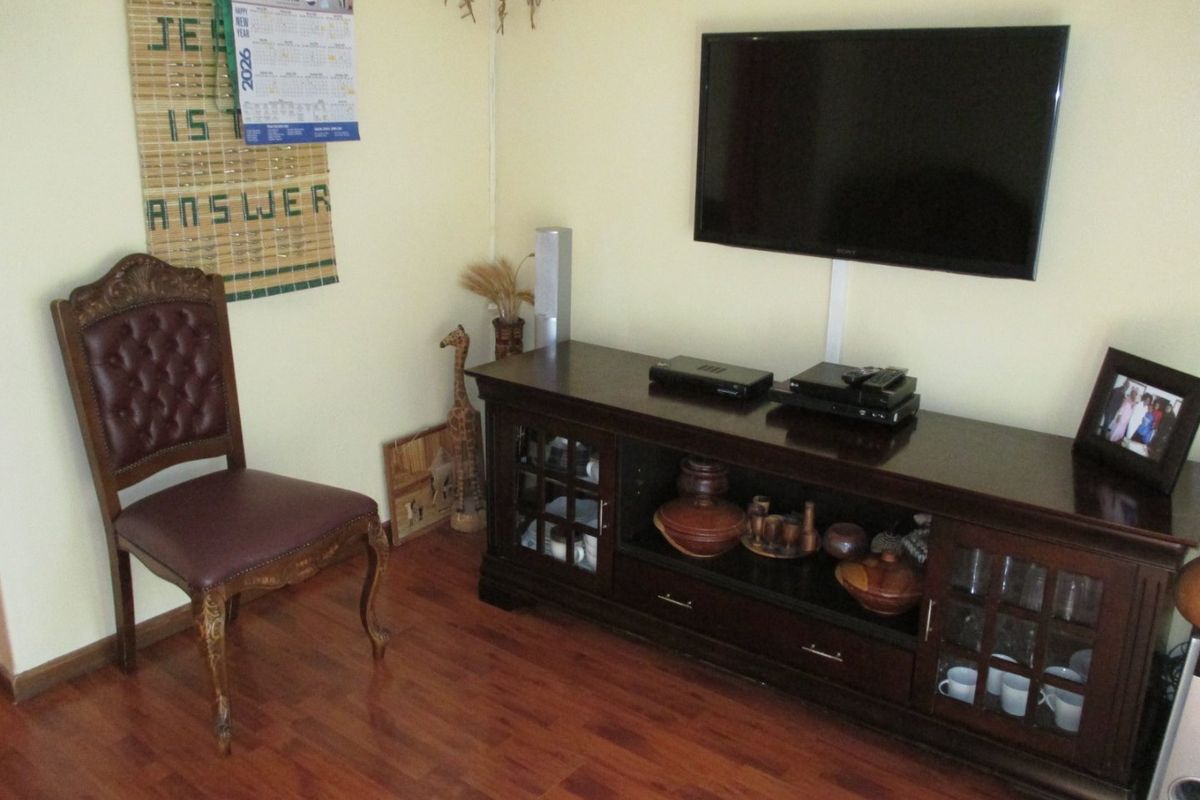A living room area featuring laminate flooring and a wall-mounted television setup.
