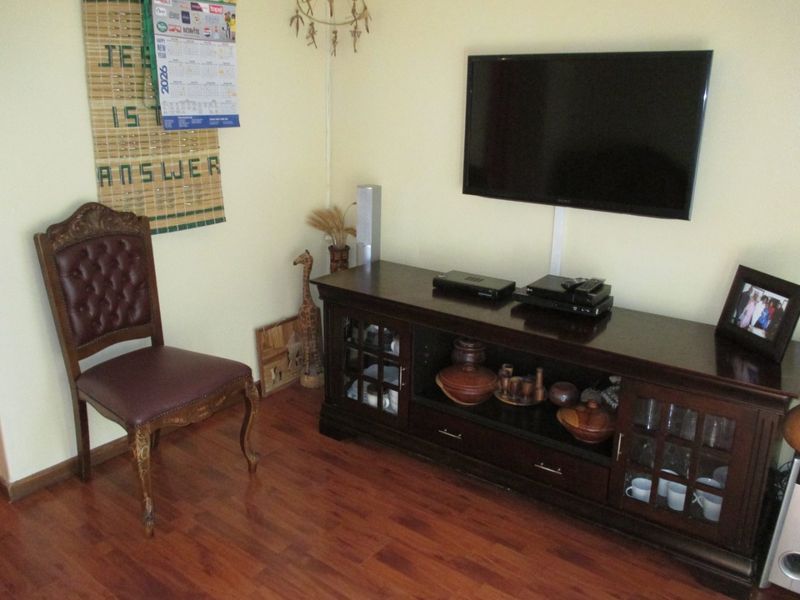 A living room area featuring laminate flooring and a wall-mounted television setup.