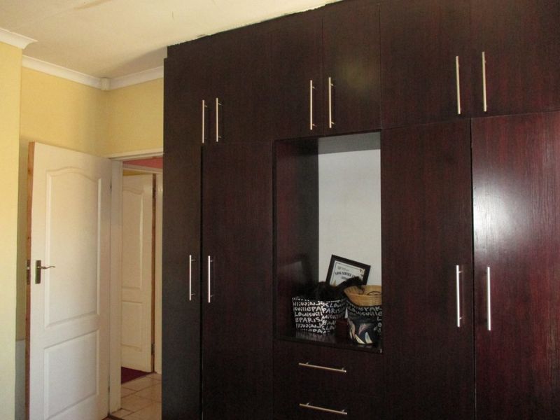A bedroom featuring dark wood built-in cupboards with modern handles and classic ceiling coving.