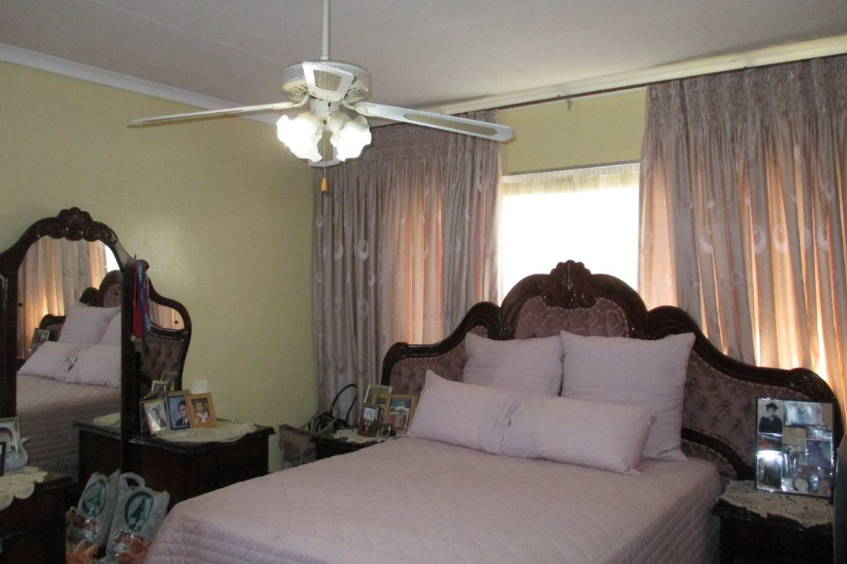 A standard bedroom featuring a ceiling fan and window treatments.