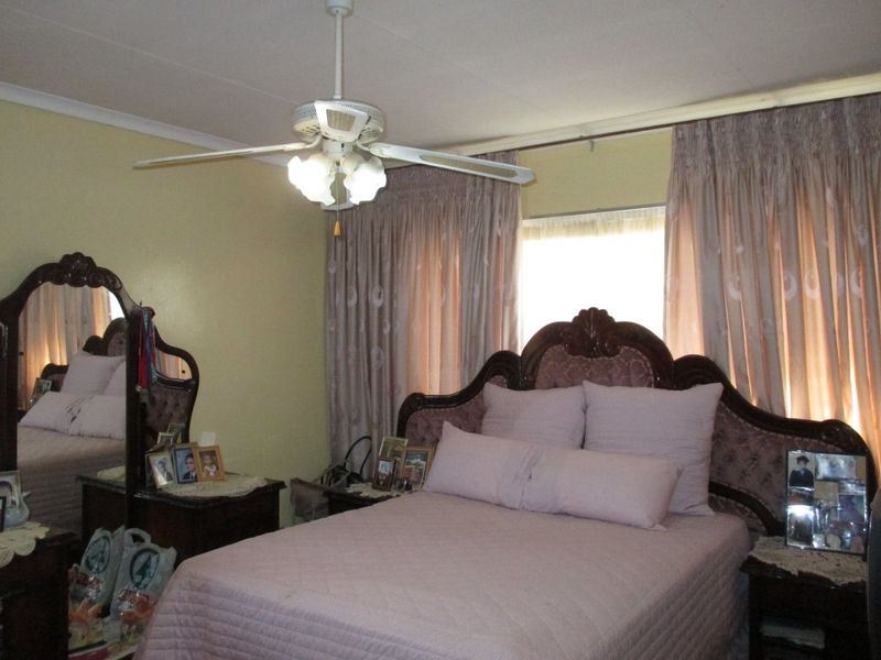 A standard bedroom featuring a ceiling fan and window treatments.