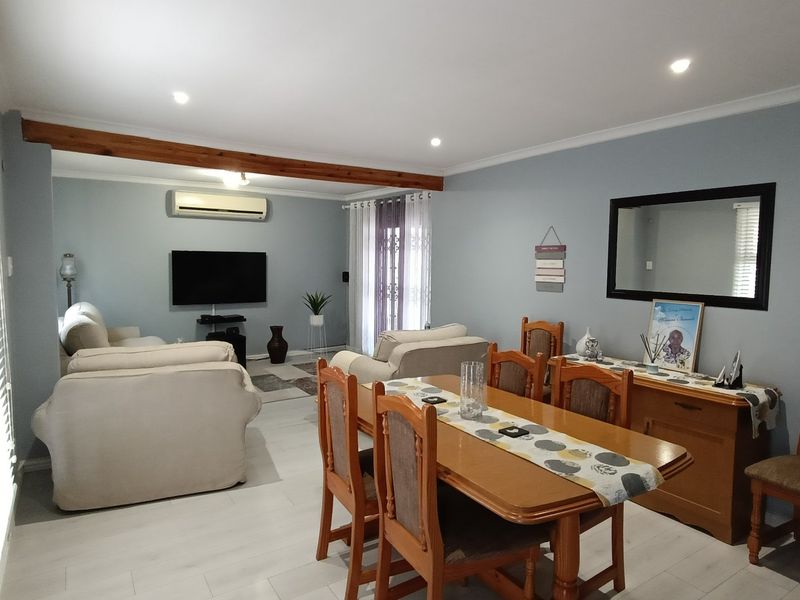 Spacious open-plan living and dining area featuring light-toned laminate flooring, recessed downlighting, and a split-system air conditioning unit.