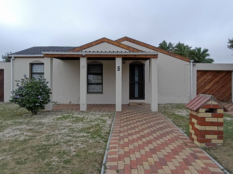 Front elevation of a single-story house featuring a covered porch, brick paved walkway, and two separate garage entrances.