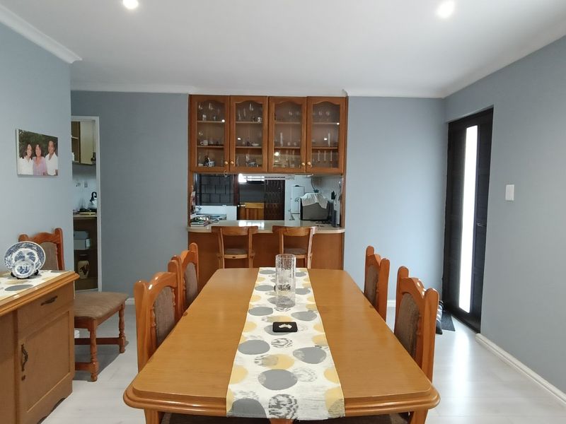 Dining room featuring laminate flooring, recessed lighting, and a built-in serving hatch with cabinetry connecting to the kitchen area.