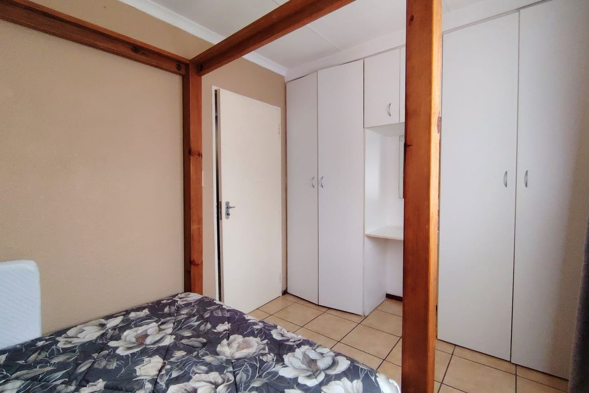 A bedroom featuring tiled flooring, neutral wall finishes, and ample built-in cupboard storage with an integrated vanity section.
