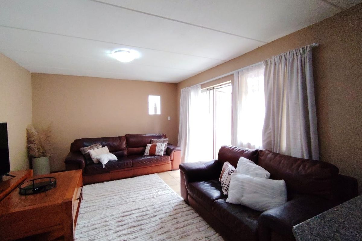 A living room featuring tiled flooring and a sliding glass door providing natural light.