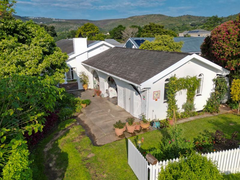 A charming single-story home featuring a white facade, tiled roof, arched patio entrance, and a well-maintained garden with a picket fence.