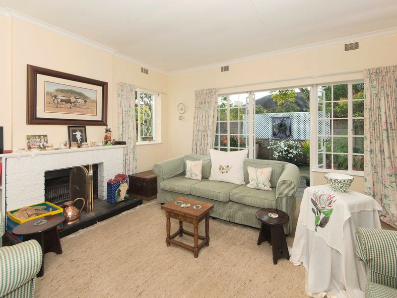 A cozy living room featuring a classic brick fireplace and large French doors that open out to the rear garden area.