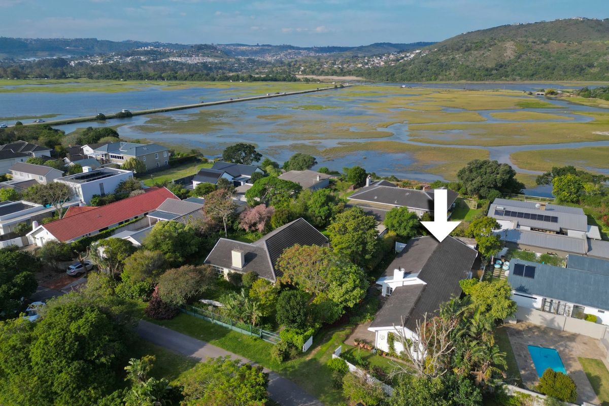Aerial view of a residential property featuring a tiled roof, chimney, and swimming pool, situated in a scenic coastal estate setting.
