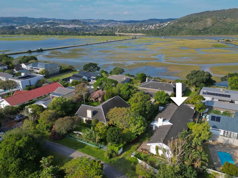 Aerial view of a residential property featuring a tiled roof, chimney, and swimming pool, situated in a scenic coastal estate setting.