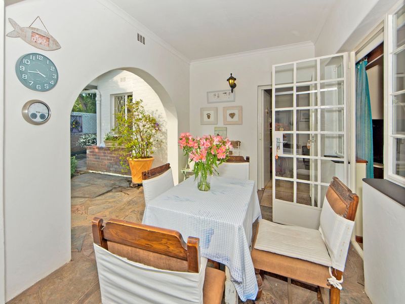 A covered patio area featuring stone flooring, an arched architectural opening, and French doors leading into the interior of the home.