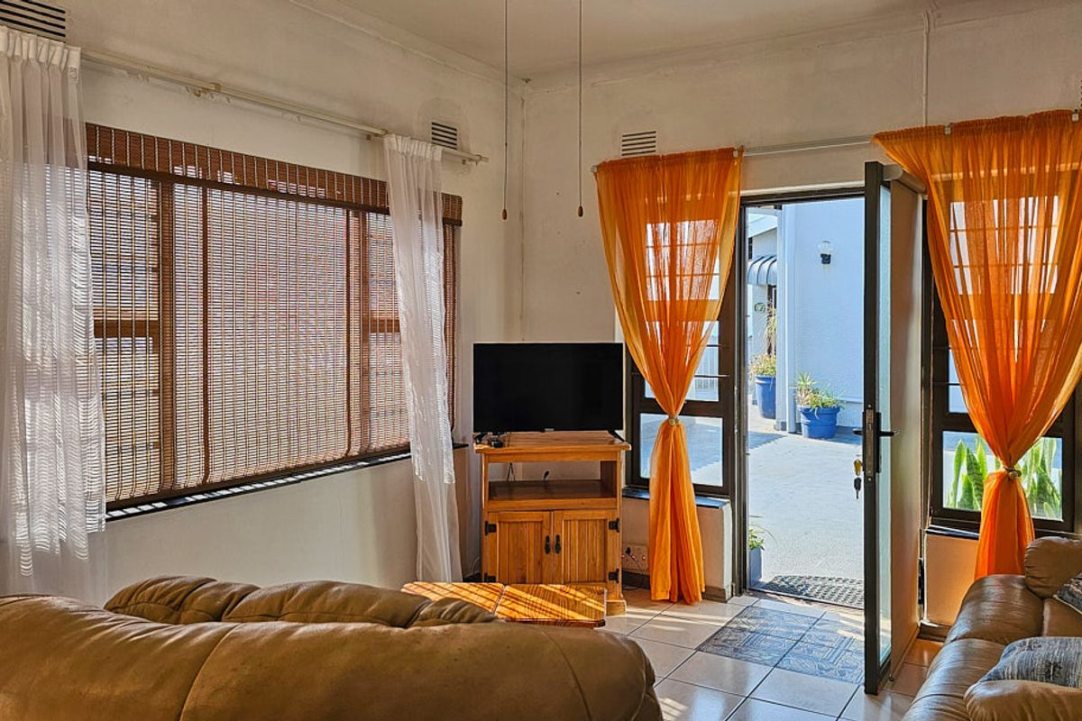 A living room featuring tiled flooring and direct access to an outdoor patio area through a glass-paneled door.
