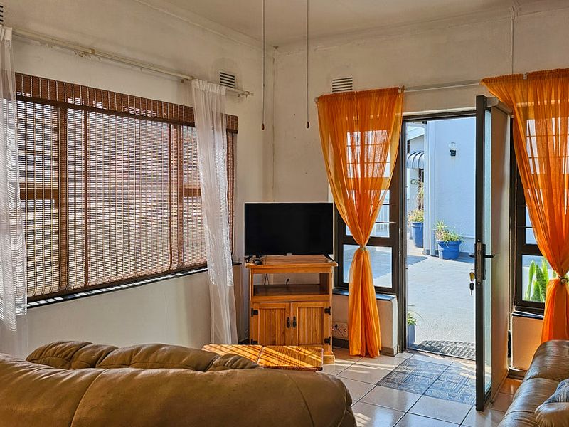 A living room featuring tiled flooring and direct access to an outdoor patio area through a glass-paneled door.