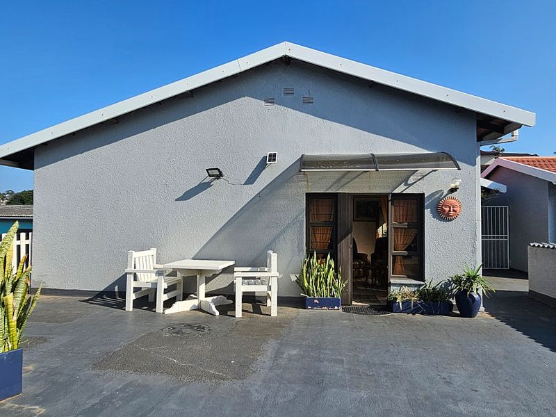 A paved outdoor patio area featuring a gabled roof structure, an entrance with a sliding door, and a protective awning.