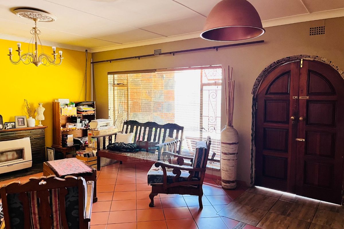 A living room featuring tiled flooring, an arched timber entrance door, a built-in fireplace, and decorative ceiling detailing.