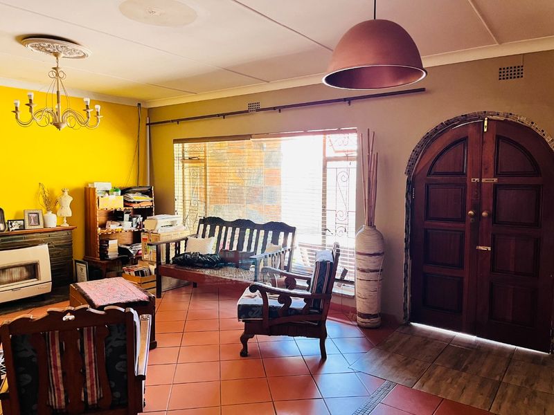A living room featuring tiled flooring, an arched timber entrance door, a built-in fireplace, and decorative ceiling detailing.