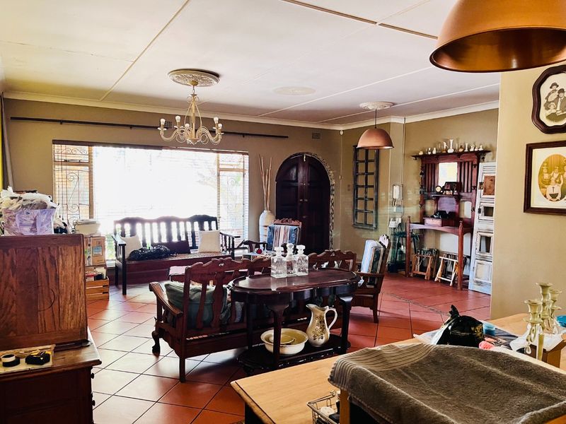 Spacious living area featuring terracotta floor tiles, an arched wooden door, and classic ceiling detailing, offering a warm and traditional atmosphere.