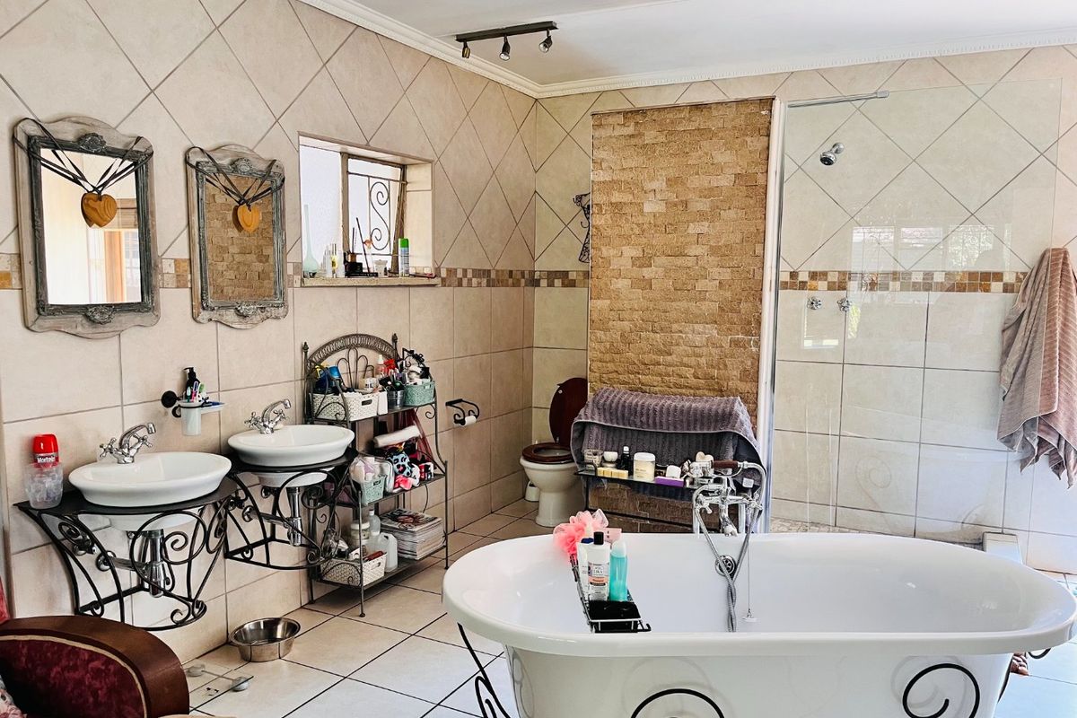 Spacious bathroom featuring a freestanding bathtub, walk-in shower, dual vessel sinks with wrought iron stands, and decorative stone wall accents.