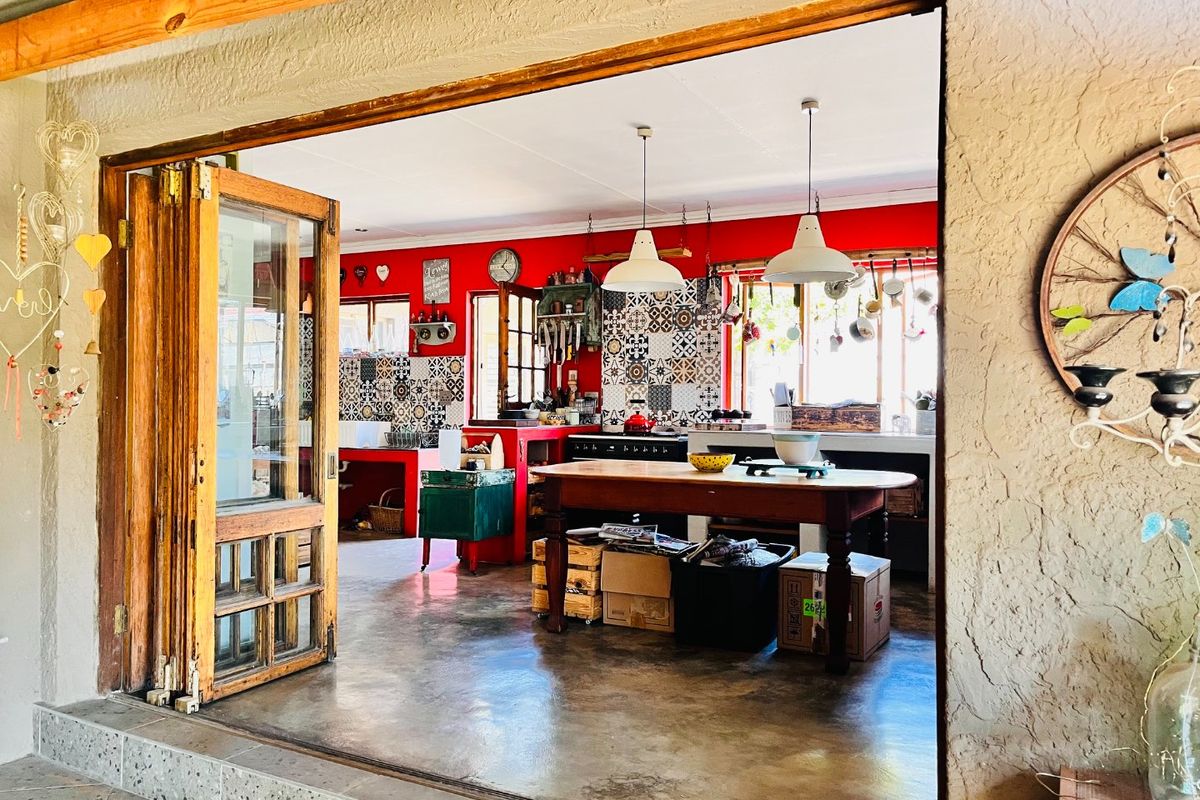 Spacious kitchen featuring polished concrete floors, vibrant red walls, patterned tile backsplashes, and large bi-fold doors opening to an outdoor area.