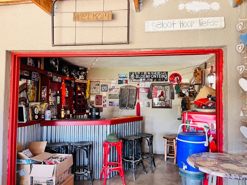 A rustic home bar area featuring a corrugated metal counter and exposed timber rafters, offering a casual entertainment space with potential for modernization.