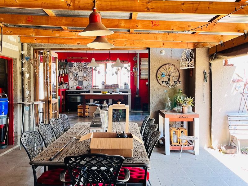 A spacious covered patio featuring exposed timber rafters, corrugated metal roofing, and tiled flooring, providing a seamless transition to the interior living space.