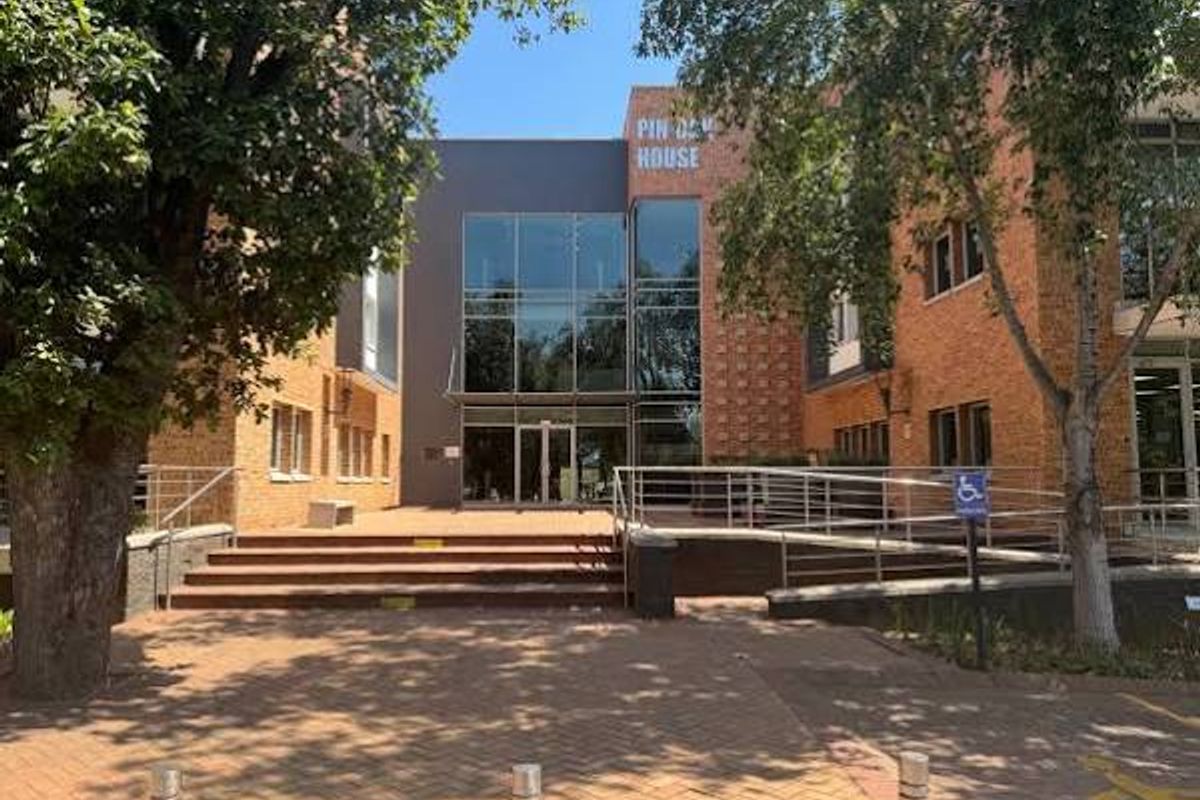 Front exterior view of Pin Oak House, featuring a modern glass facade, brick masonry, and accessible entrance with paved approach.