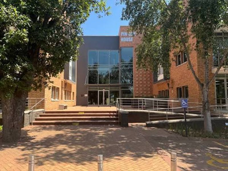 Front exterior view of Pin Oak House, featuring a modern glass facade, brick masonry, and accessible entrance with paved approach.