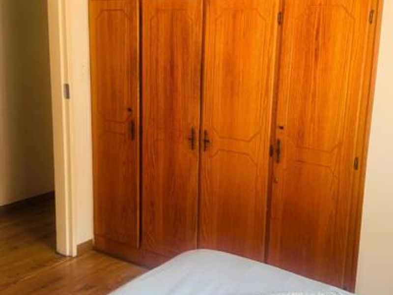 Bedroom featuring floor-to-ceiling built-in wooden cupboards and laminate flooring.