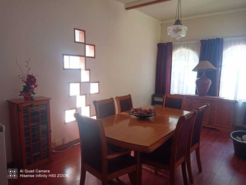 A dining room featuring laminate flooring, unique decorative wall cutouts, and arched windows, providing a functional space for family meals.