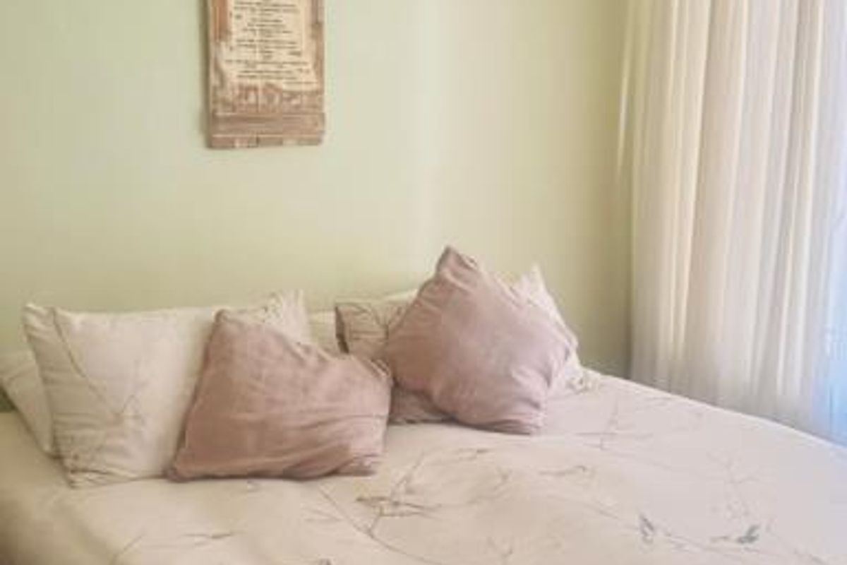 A cozy bedroom featuring neutral wall tones, classic ceiling cornice detailing, and window treatments.