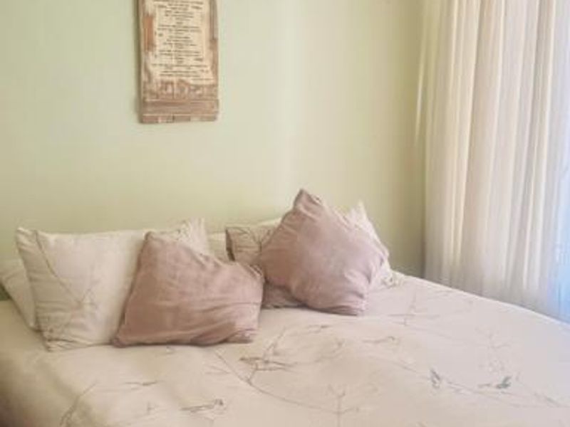 A cozy bedroom featuring neutral wall tones, classic ceiling cornice detailing, and window treatments.