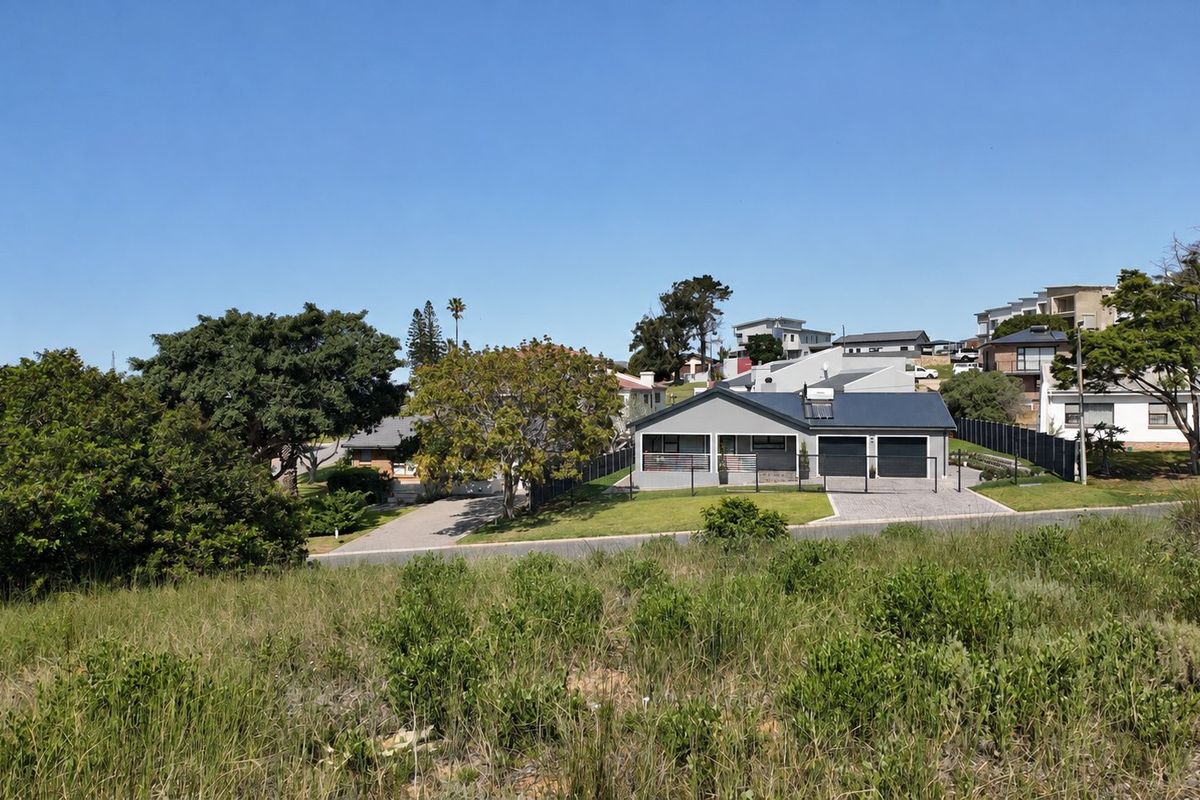 A view of a residential property featuring a double garage, paved driveway, and metal roof, situated in a suburban neighborhood setting.