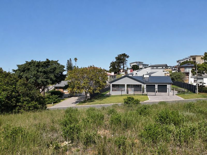 A view of a residential property featuring a double garage, paved driveway, and metal roof, situated in a suburban neighborhood setting.