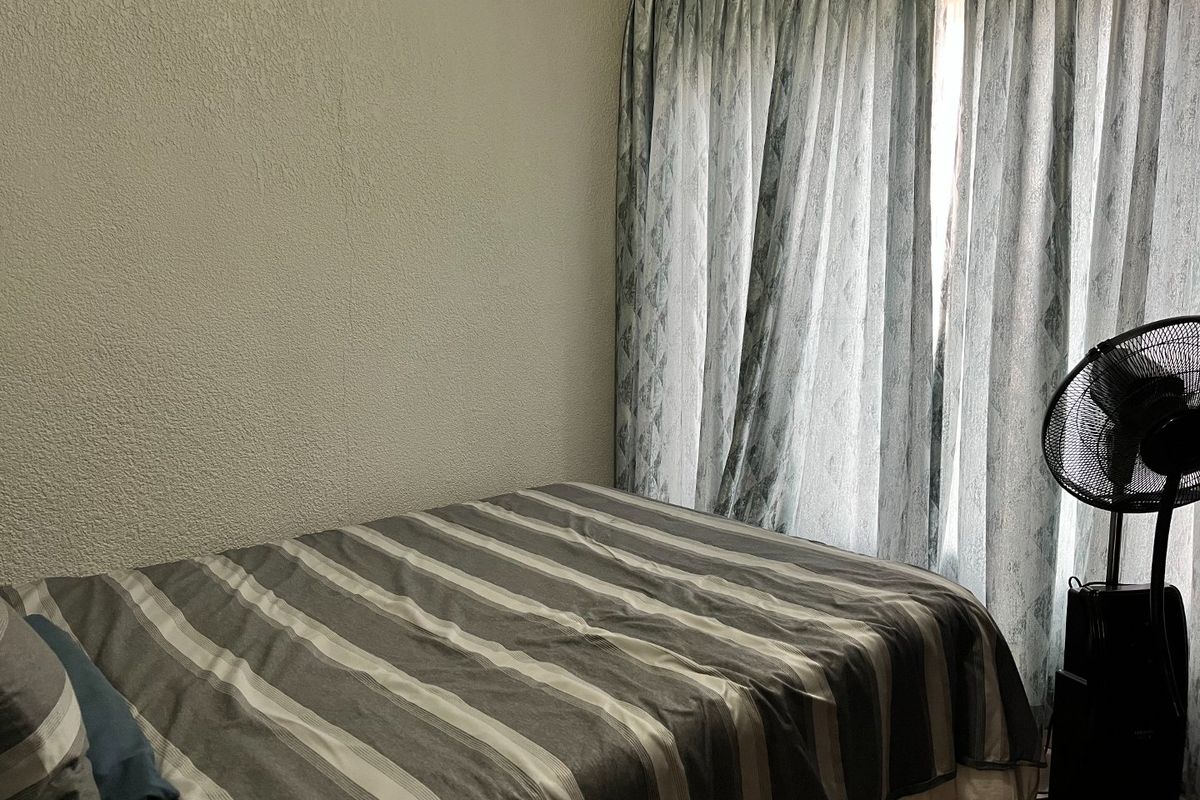 A bedroom featuring textured walls and floor-to-ceiling curtains, providing a functional and private sleeping space.