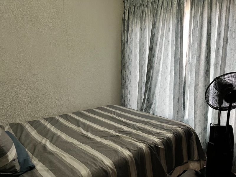 A bedroom featuring textured walls and floor-to-ceiling curtains, providing a functional and private sleeping space.