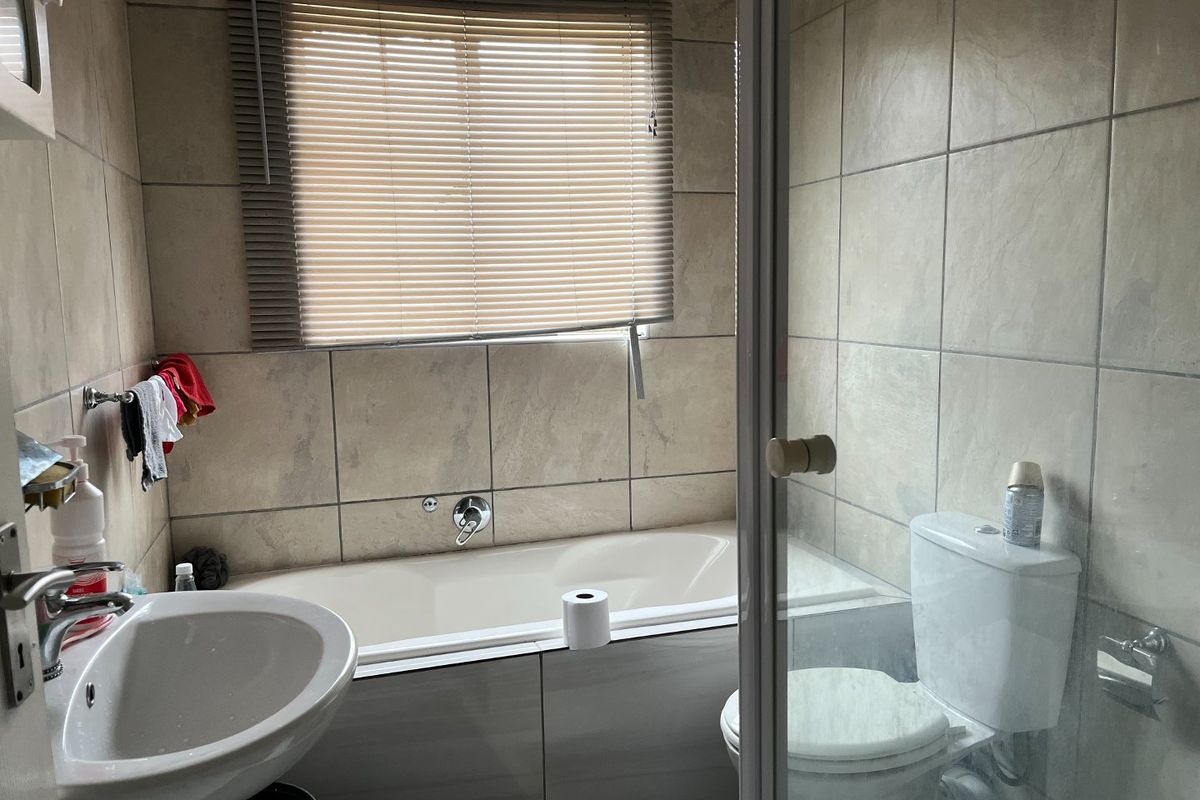 A functional bathroom featuring a bathtub, pedestal basin, toilet, and tiled walls, providing essential amenities in a compact layout.