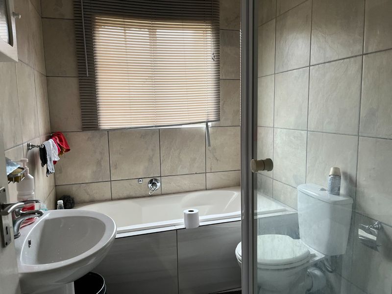 A functional bathroom featuring a bathtub, pedestal basin, toilet, and tiled walls, providing essential amenities in a compact layout.